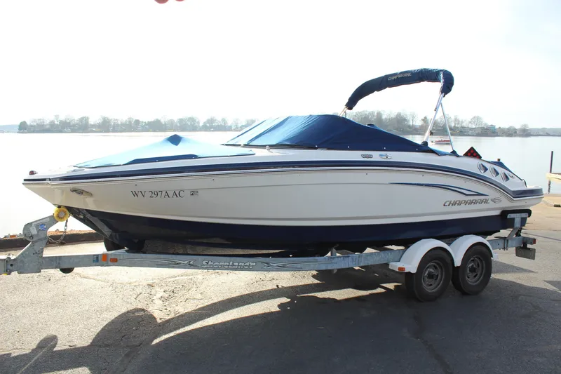 Slide: The Image of 2011 Chaparral 216 SSi boat on trailer by a lake, covered and ready for transport. - 18