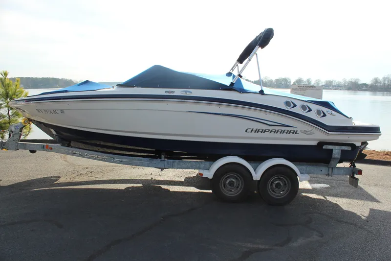 Slide: The Image of 2011 Chaparral 216 SSi boat on trailer by a lake, covered and ready for transport. - 19