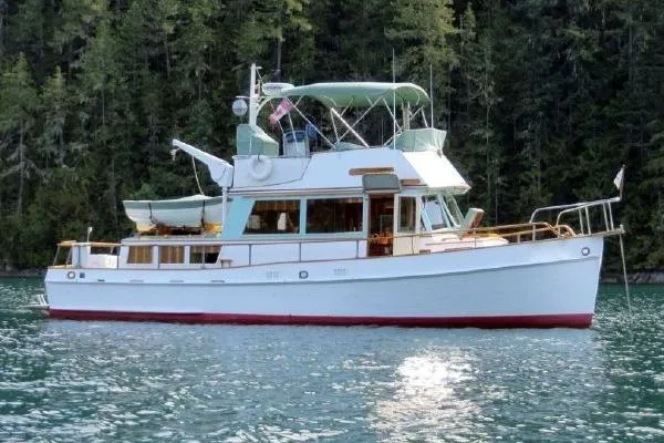 The Image of 1973 Grand Banks 36 Classic yacht on serene water with forest backdrop. - 0