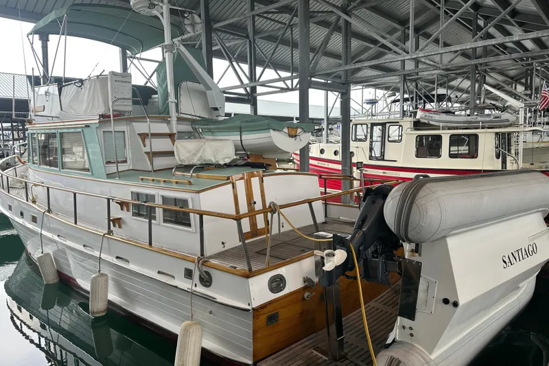 Slide: The Image of 1973 Grand Banks 36 Classic yacht docked in a marina, featuring a dinghy named Santiago. - 12