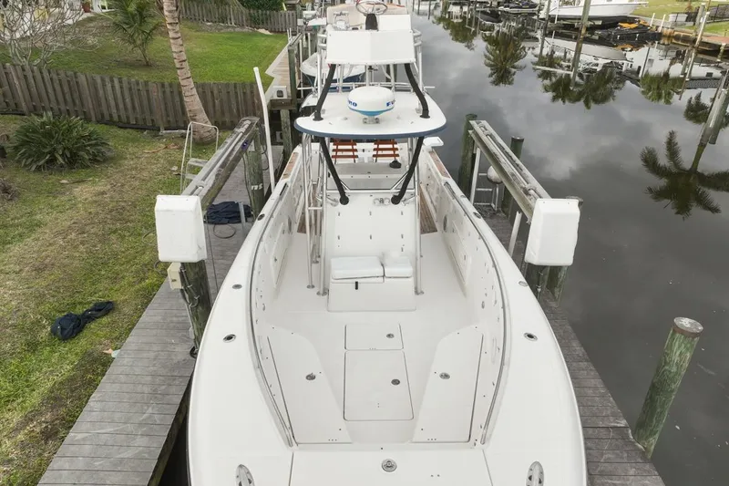 Slide: The Image of 2007 Triton 351 CC boat docked by a calm waterfront, surrounded by greenery. - 10