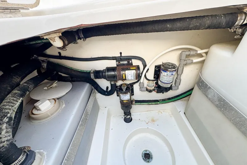 Slide: The Image of 2007 Triton 351 CC boat plumbing system with hoses and pumps in a storage compartment. - 101