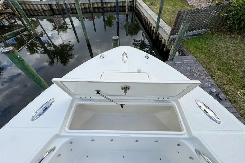 Slide: The Image of 2007 Triton 351 CC boat with open storage compartment, docked by a calm waterfront. - 107