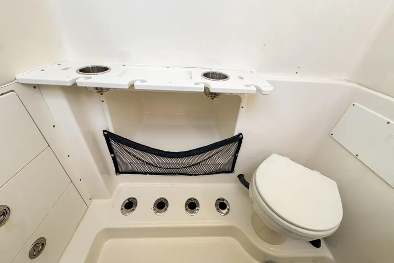 Slide: The Image of 2007 Triton 351 CC boat bathroom with toilet, storage, and cup holders. - 118