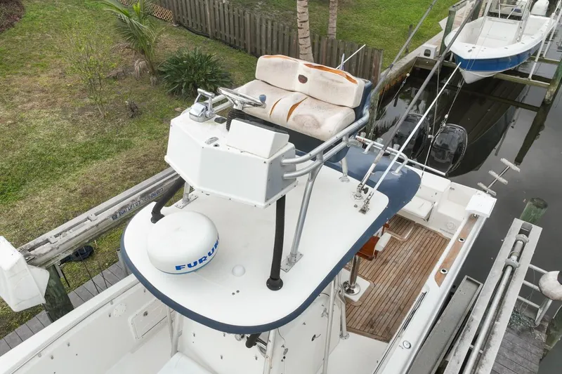 Slide: The Image of 2007 Triton 351 CC boat with elevated helm and seating, docked near a grassy area. - 125