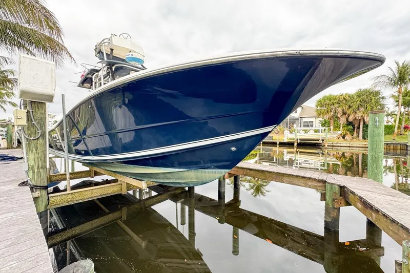 Slide: The Image of 2007 Triton 351 CC boat on lift, dockside view with palm trees. - 20