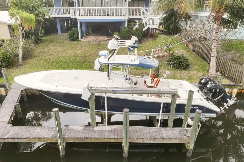 The Image of 2007 Triton 351 CC boat docked near waterfront home with lush greenery. - 0