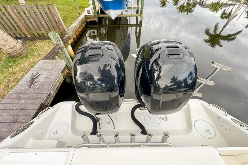 Slide: The Image of 2007 Triton 351 CC boat with dual outboard motors docked by a wooden pier. - 22