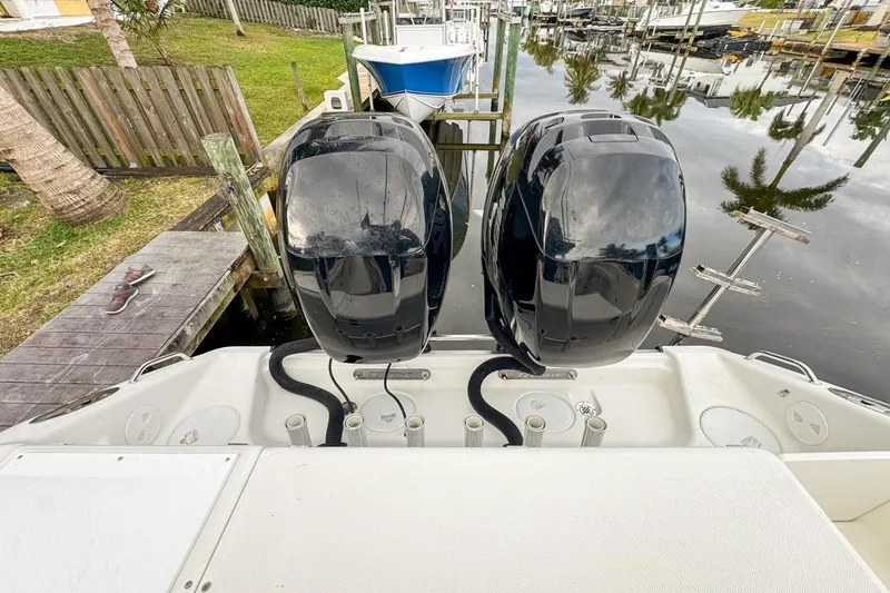 Slide: The Image of 2007 Triton 351 CC boat with dual outboard motors docked by a wooden pier. - 23