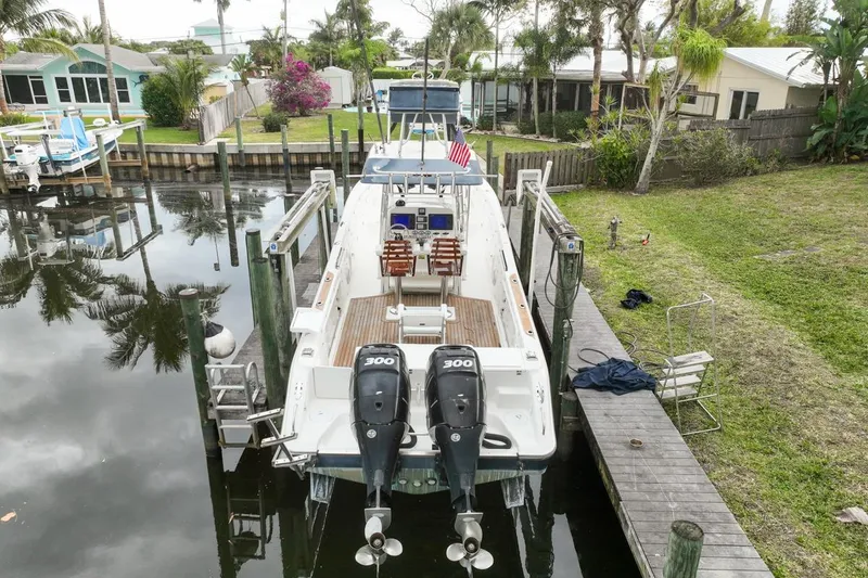 Slide: The Image of 2007 Triton 351 CC boat docked, featuring dual 300 horsepower engines, in a serene residential canal. - 3