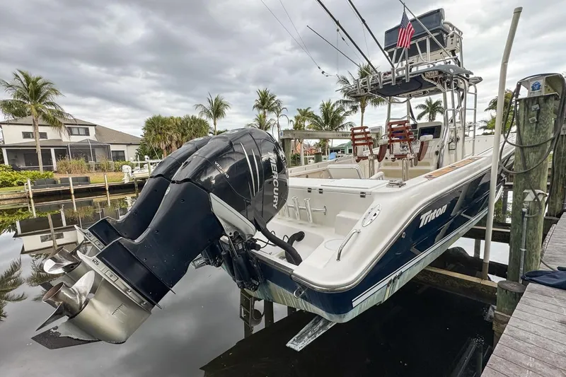 Slide: The Image of 2007 Triton 351 CC boat with dual Mercury engines docked by palm trees. - 4