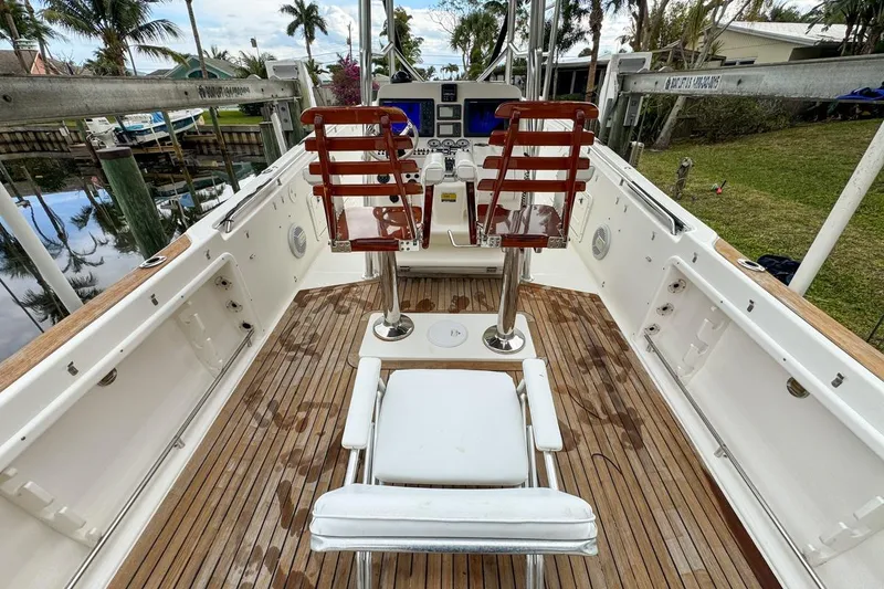 Slide: The Image of 2007 Triton 351 CC boat interior with wooden deck and seating, docked near palm trees. - 41