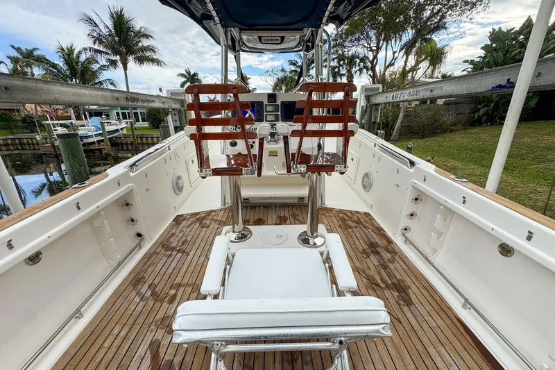 Slide: The Image of 2007 Triton 351 CC boat interior with wooden deck and seating, docked near palm trees. - 43