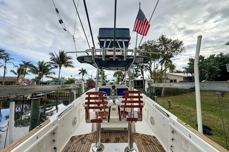 Slide: The Image of 2007 Triton 351 CC boat with American flag, docked near palm trees and waterfront homes. - 45