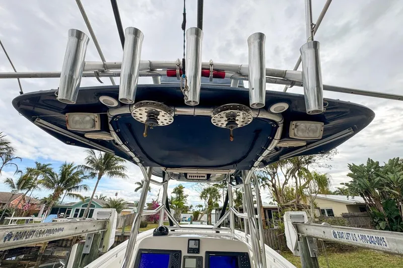 Slide: The Image of 2007 Triton 351 CC boat with rod holders and electronics, docked near palm trees. - 66