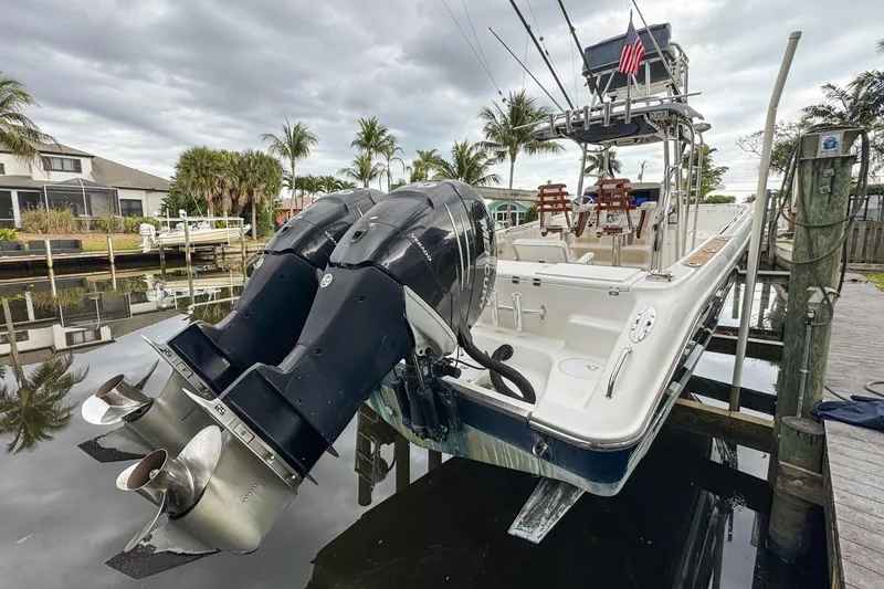 Slide: The Image of 2007 Triton 351 CC boat with dual outboard engines docked near palm trees. - 8