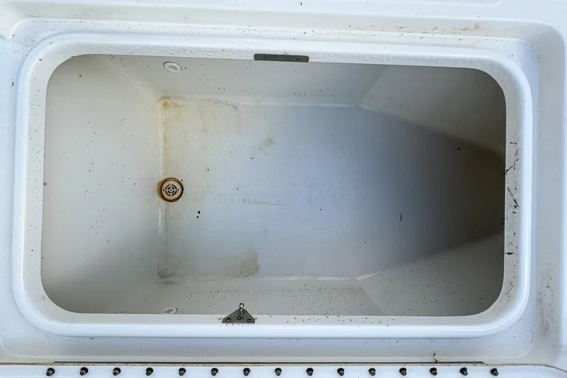 Slide: The Image of Empty storage compartment on a 2007 Triton 351 CC boat, showing drain and slight discoloration. - 98
