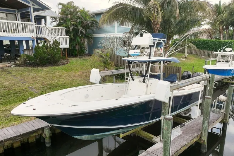 The Image of 2007 Triton 351 CC boat docked near waterfront homes with lush greenery. - 1