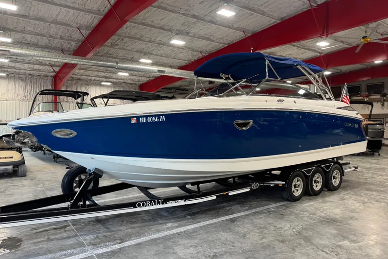 Slide: The Image of 2011 Cobalt boat with blue hull on trailer in indoor storage facility. - 2