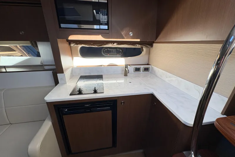 Slide: The Image of 2018 Sea Ray Sundancer 350 Coupe kitchen with stove, microwave, and sleek cabinetry. - 15
