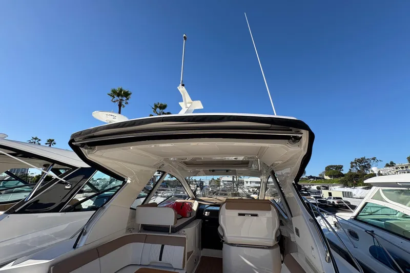Slide: The Image of 2018 Sea Ray Sundancer 350 Coupe interior with open cockpit, docked under clear blue sky. - 8