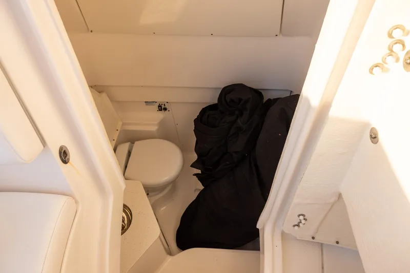 Slide: The Image of 2020 Robalo R302 Center Console boat interior with compact toilet and storage area. - 11