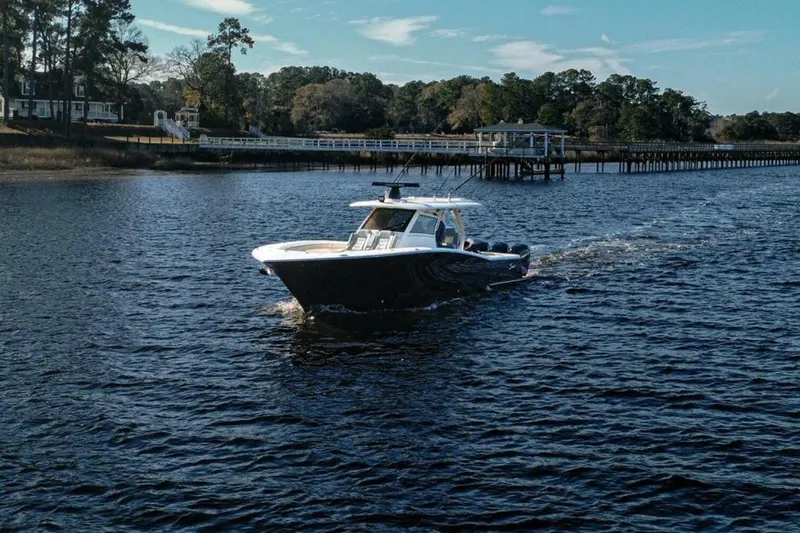 Slide: The Image of 2020 Scout 380 LXF boat cruising on a scenic river near a wooden dock. - 4