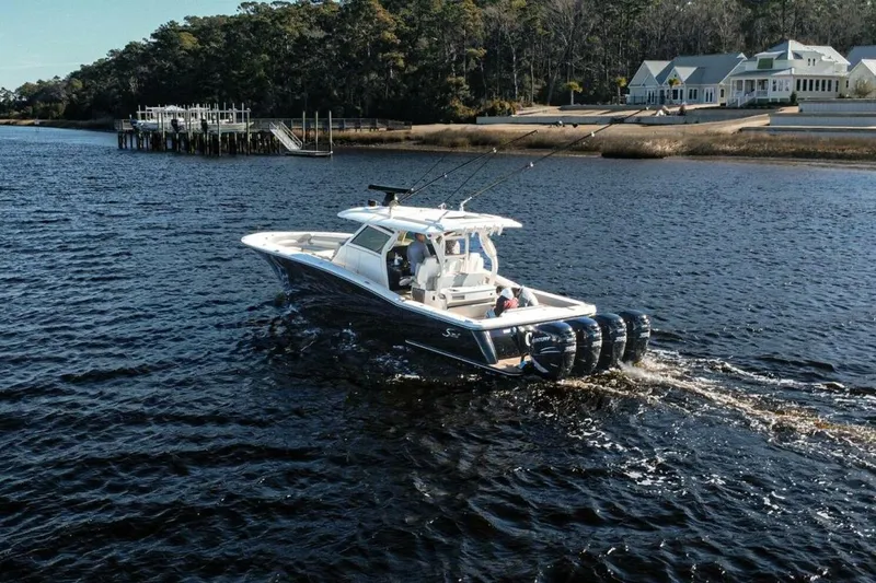 Slide: The Image of 2020 Scout 380 LXF boat cruising on a scenic river near waterfront homes. - 5