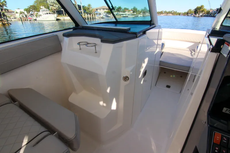 Slide: The Image of 2023 Pursuit DC 295 Dual Console interior with seating and cup holders, dockside view. - 13