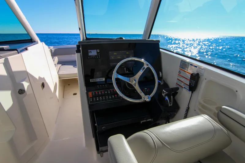 Slide: The Image of 2023 Pursuit DC 295 Dual Console boat interior with steering wheel and ocean view. - 32