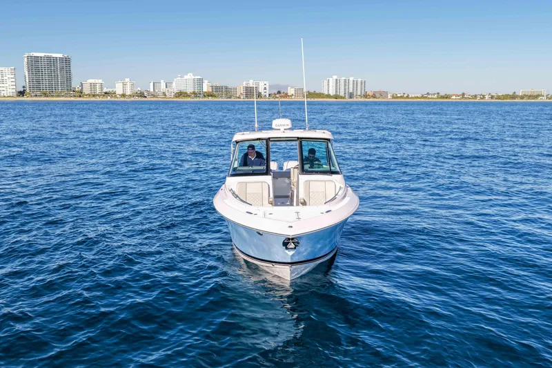 Slide: The Image of 2023 Pursuit DC 295 Dual Console boat on open water with city skyline backdrop. - 41