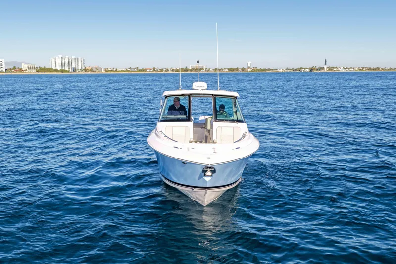 Slide: The Image of 2023 Pursuit DC 295 Dual Console boat on open water, with city skyline in background. - 44
