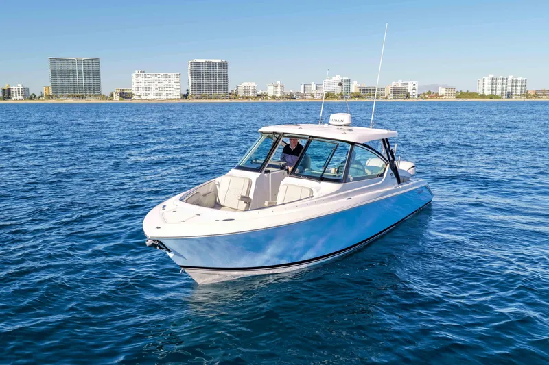 Slide: The Image of 2023 Pursuit DC 295 Dual Console boat on blue ocean with city skyline backdrop. - 45