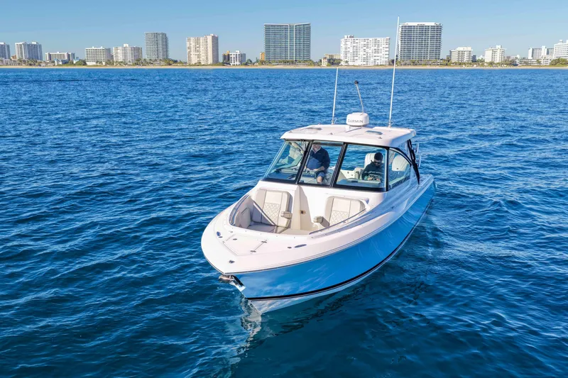 Slide: The Image of 2023 Pursuit DC 295 Dual Console boat on blue ocean with city skyline background. - 49