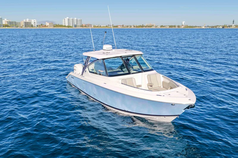 Slide: The Image of 2023 Pursuit DC 295 Dual Console boat on open water, near coastal cityscape. - 51