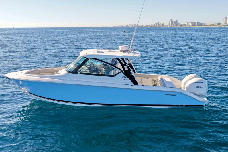 Slide: The Image of 2023 Pursuit DC 295 Dual Console boat on open water, city skyline in background. - 57