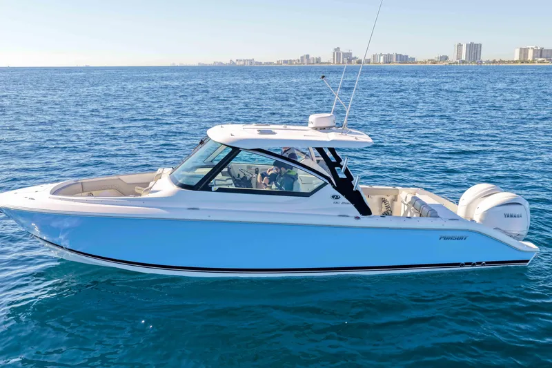 Slide: The Image of 2023 Pursuit DC 295 Dual Console boat on open water, city skyline in background. - 58