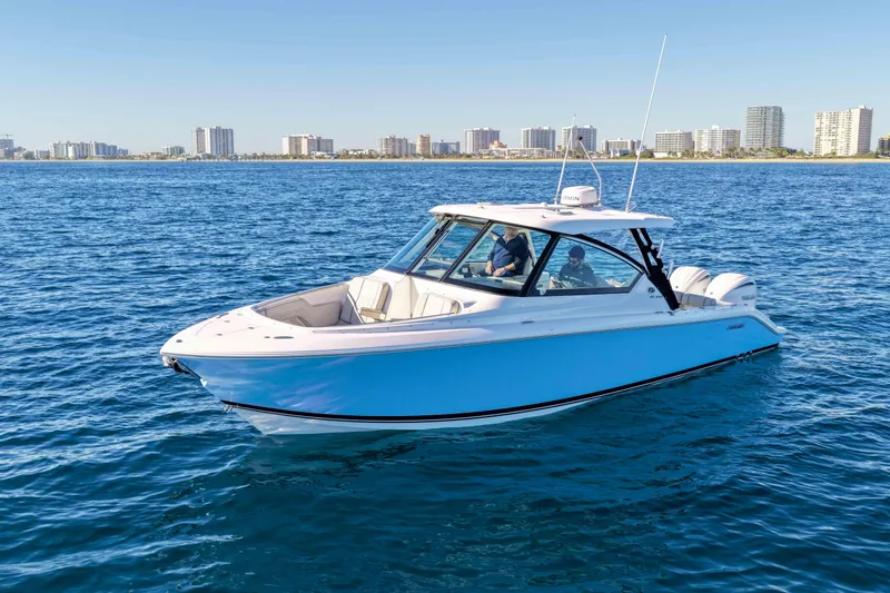 Slide: The Image of 2023 Pursuit DC 295 Dual Console boat cruising on open water near city skyline. - 60