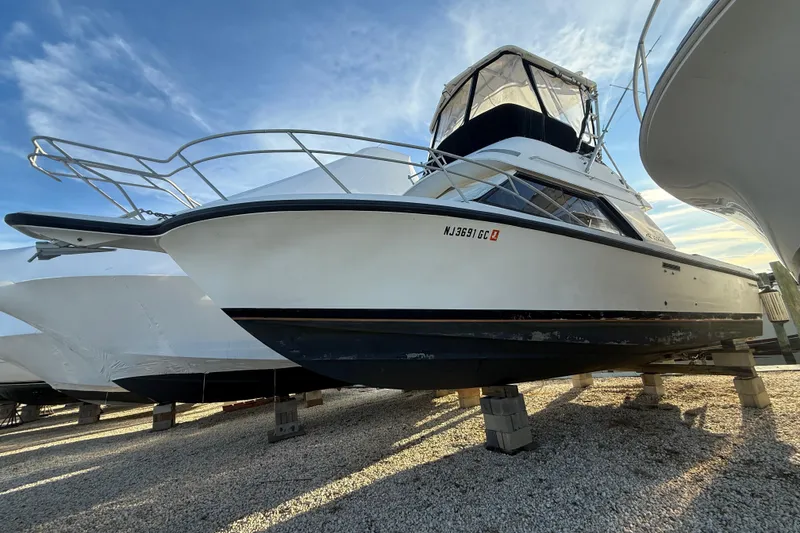 The Image of 1988 Phoenix 29 SFX Convertible boat on dry dock under a clear sky. - 1