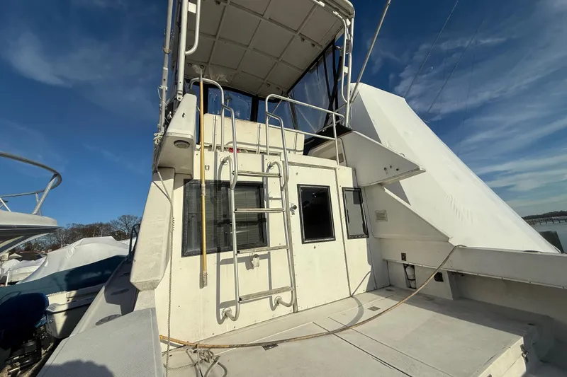 Slide: The Image of 1988 Phoenix 29 SFX Convertible boat with upper deck and ladder under clear sky. - 4