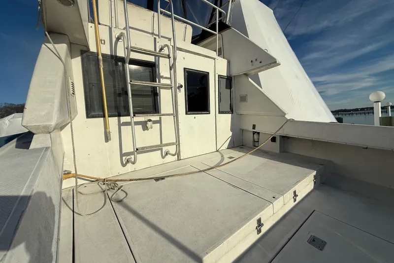 Slide: The Image of 1988 Phoenix 29 SFX Convertible boat deck with ladder and window, under clear sky. - 6