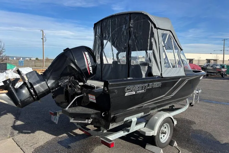 Slide: The Image of 2024 Crestliner 1650 Hawk boat with Mercury engine on trailer, outdoor setting. - 1
