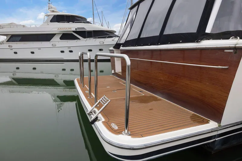 Slide: The Image of 1998 Pacific Mariner 65 yacht docked, featuring a sleek wooden deck and stainless steel railings. - 3