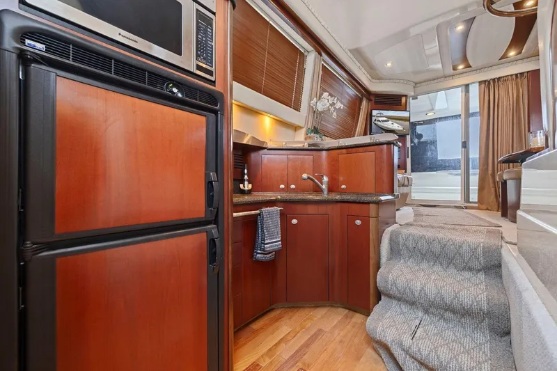 Slide: The Image of Luxurious 2005 Sea Ray 420 Sedan Bridge interior with modern kitchen and elegant wood finishes. - 10