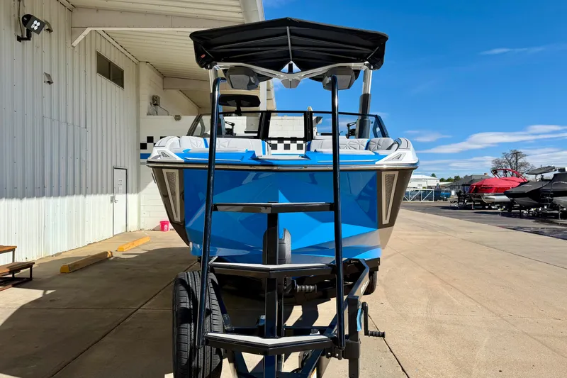 Slide: The Image of 2026 Nautique Super Air Nautique G23 Paragon boat in blue, parked outdoors. - 6