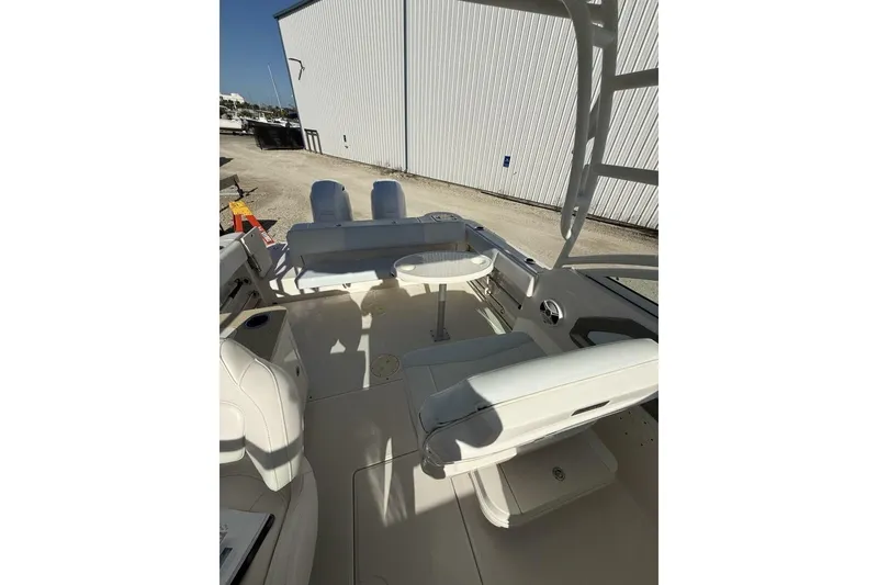 Slide: The Image of 2018 Robalo R247 Dual Console boat interior with seating and table, docked near a building. - 14