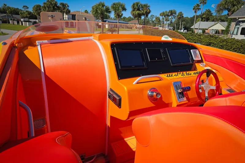 Slide: The Image of Vibrant orange interior of a 2005 Outerlimits 51 Sport Yacht with modern dashboard controls. - 12