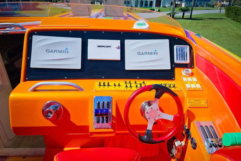 Slide: The Image of 2005 Outerlimits 51 Sport Yacht dashboard with Garmin and Mercury displays, vibrant orange interior. - 15