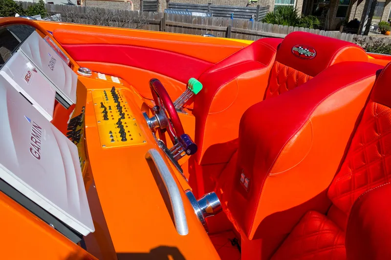 Slide: The Image of 2005 Outerlimits 51 Sport Yacht cockpit with vibrant orange and red seating, Garmin displays. - 16