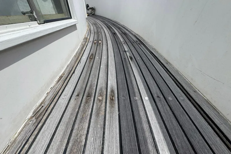 Slide: The Image of Teak deck of 1989 Grand Banks 42 Motor Yacht, showing weathered wood and curved design. - 10